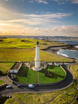 A stunning aerial view of Girdle Ness Lighthouse amidst lush landscape and coastline in Aberdeen, Scotland.